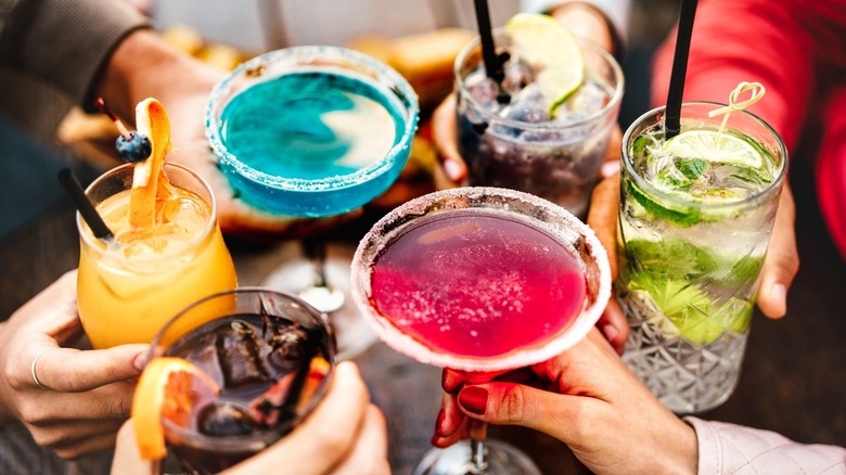 People toasting with colorful cocktails