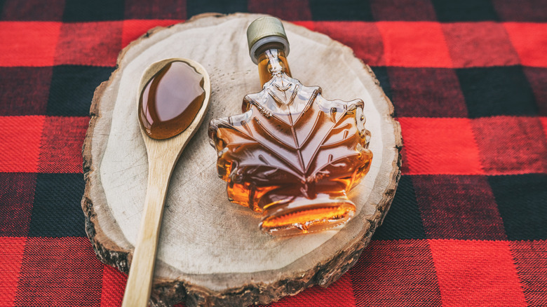 Bottle of maple syrup next to a wooden spoon