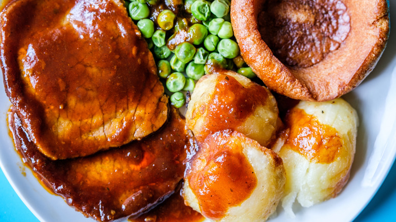 Sunday roast with sliced beef, potatoes, peas, and Yorkshire pudding