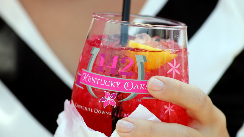 An Oaks Lily cocktail in a glass with a black straw