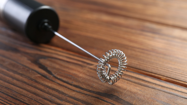 Close-up of a handheld milk frother on a wood table