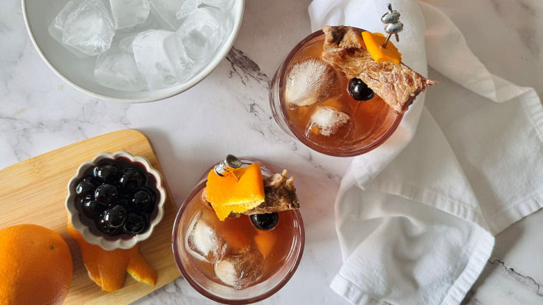 brown cocktails garnished with steak and orange