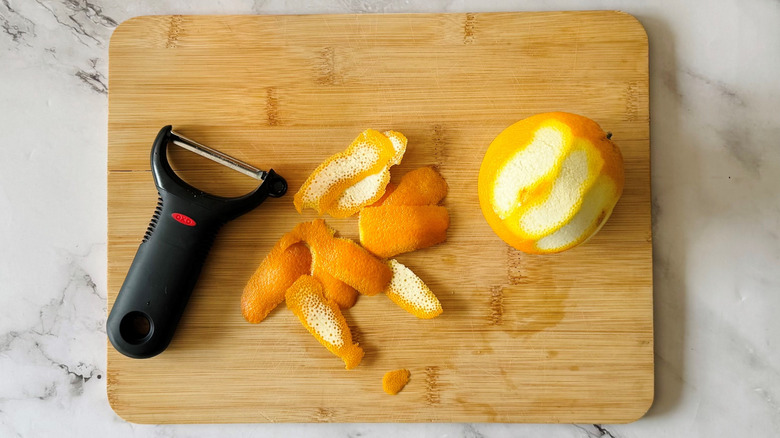 partially peeled orange on a wooden board