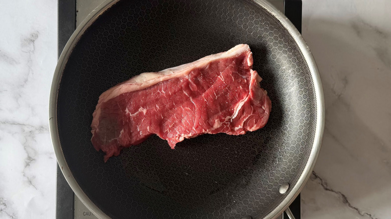 raw steak in a frying pan