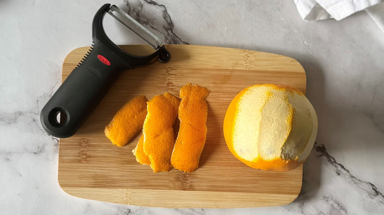 partially peeled orange on a wooden board