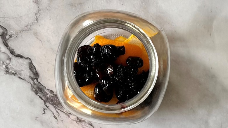 cherries and orange peels in a glass jar