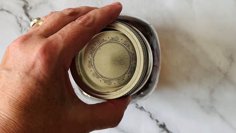 hand touching a jar lid
