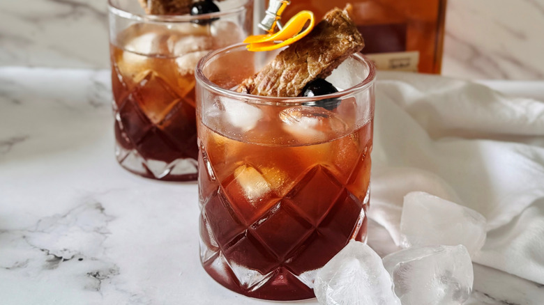 brown cocktails garnished with steak and orange