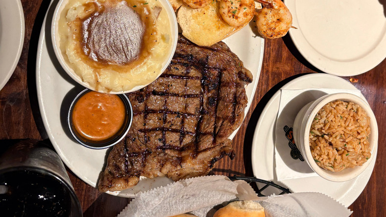 A Texas Roadhouse dinner complete with a steak, shrimp, mashed potatoes, and rice.