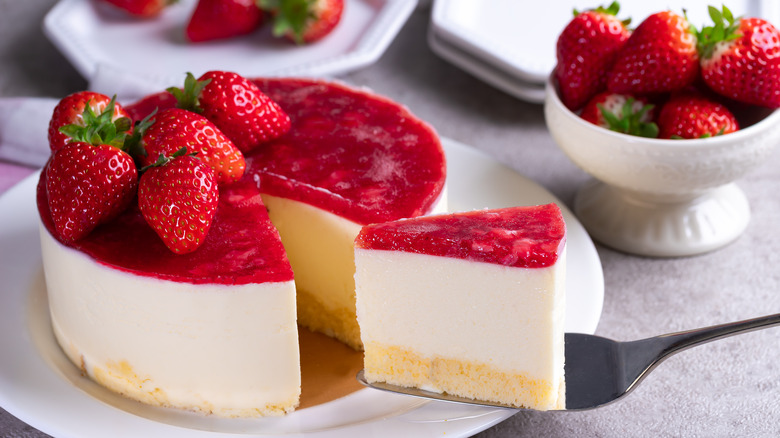 Strawberry cheesecake with one slice being removed 
