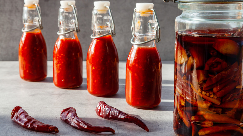 Bottles of hot sauce alongside peppers
