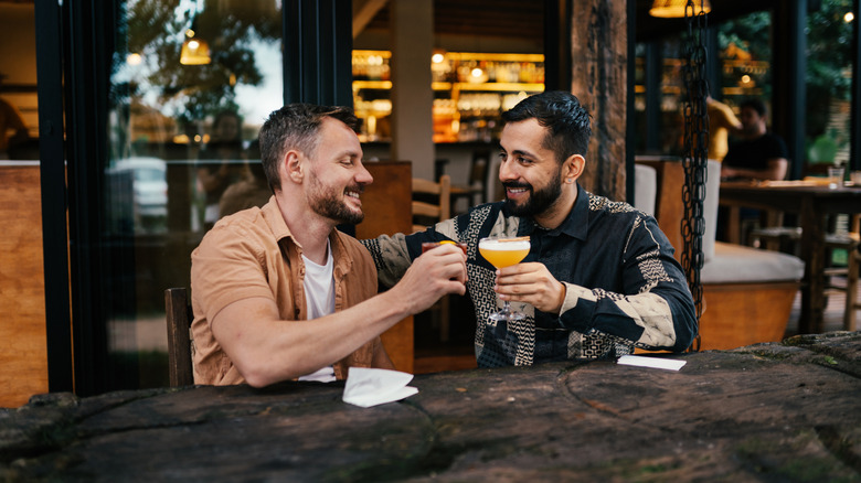 Couple toasting with drinks at cocktail bar