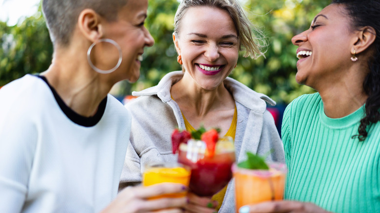 Three women, laughing with cocktails