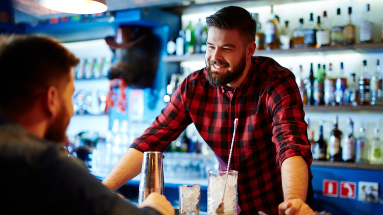 Man, viewed from behind, talking to smiling bartender