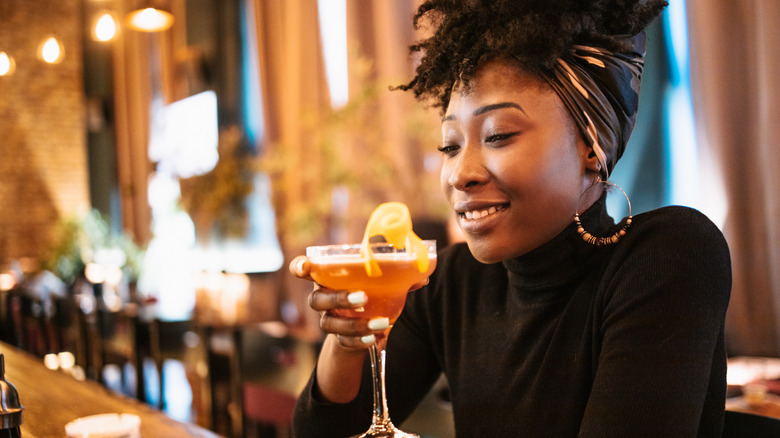 Woman holding cocktail in a bar, about to take a sip