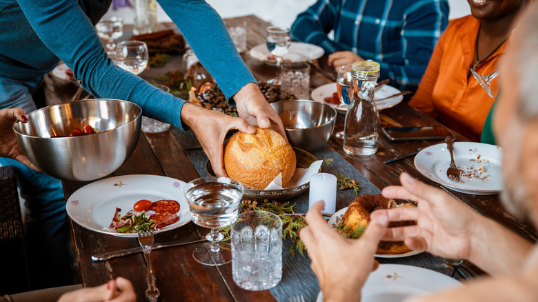 Hands placing bread on a dinner table