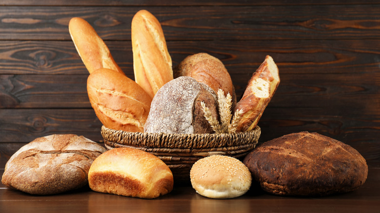 Various types of bread on a wooden table and in a basket