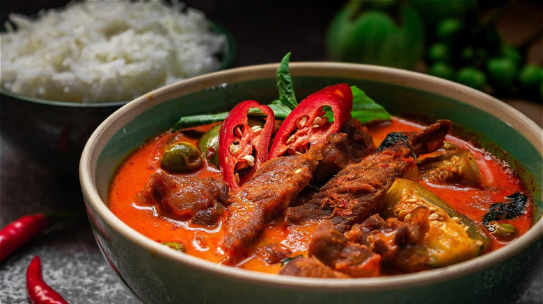 thai dish with spices and peppers next to bowl of rice