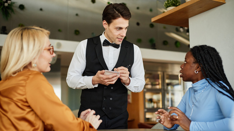 Two women ordering at a restaurant, one talking to the waiter