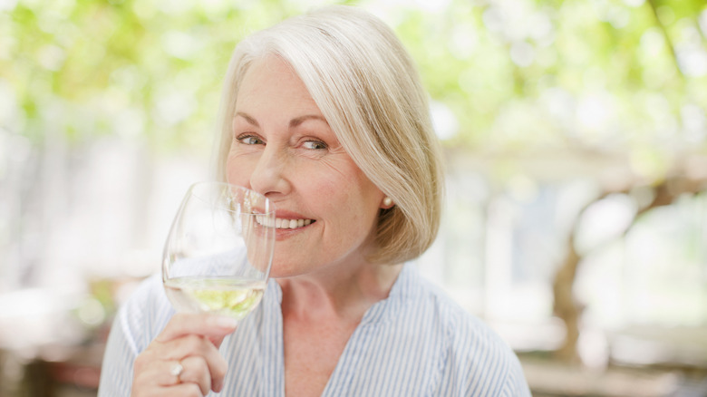 Woman smiling with a glass of white wine outside