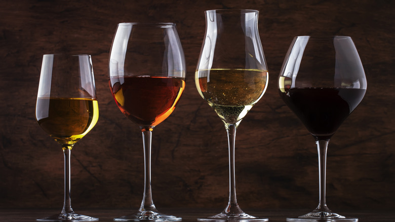 Four different styles of wine glasses filled with various types of wine