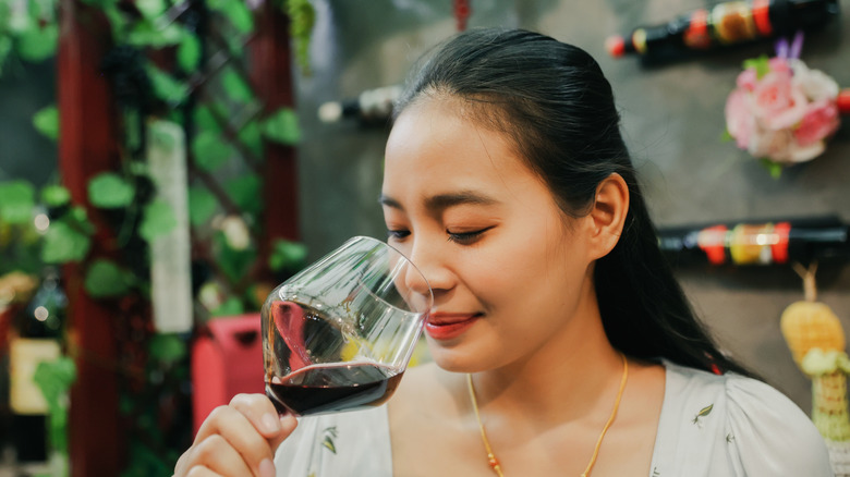 Woman smelling a glass of red wine at a restaurant