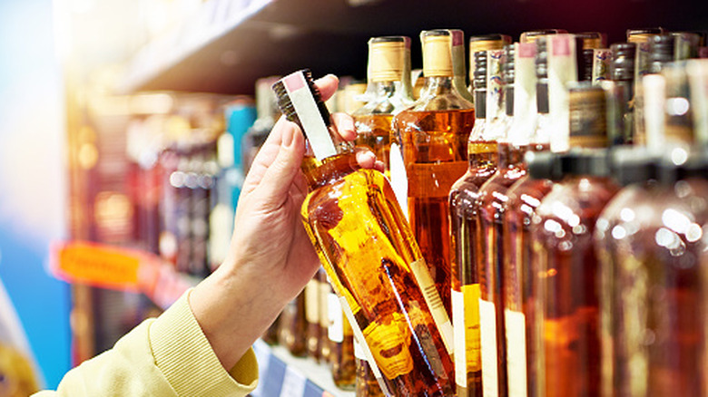 Hand picking bottle of bourbon off shelf