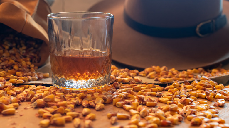 A glass of bourbon alongside a scattering of dried grains