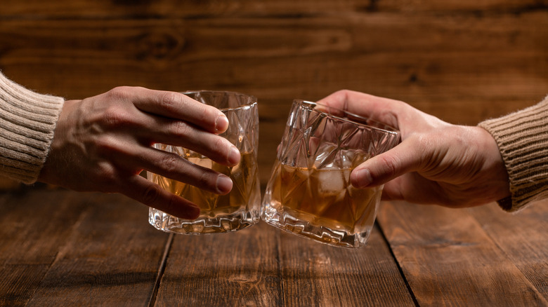Two people toasting with bourbon