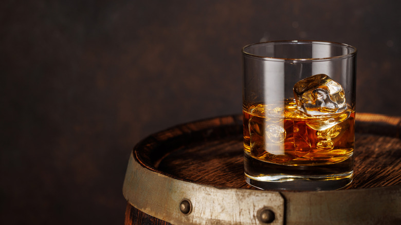 Glass of bourbon sitting on a wooden barrel