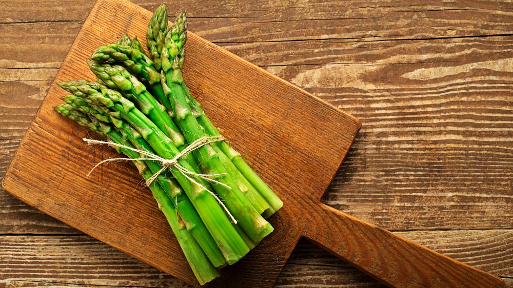 bundle of asparagus on cutting board