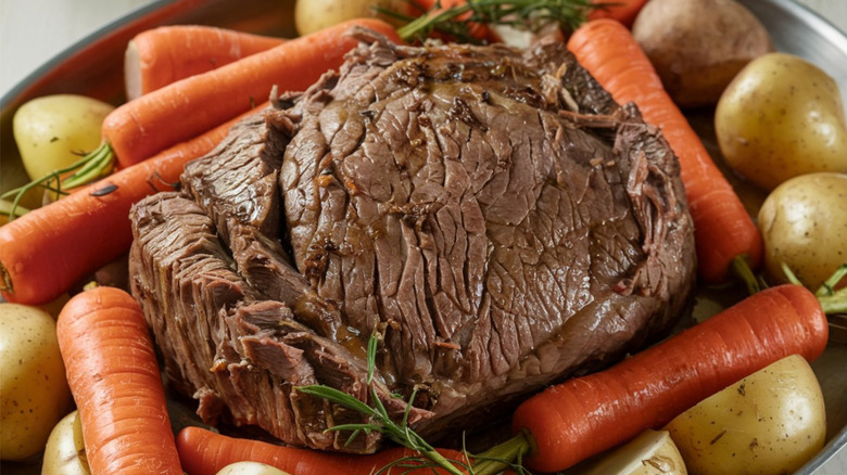 chuck pot roast in pan with carrots and potatoes