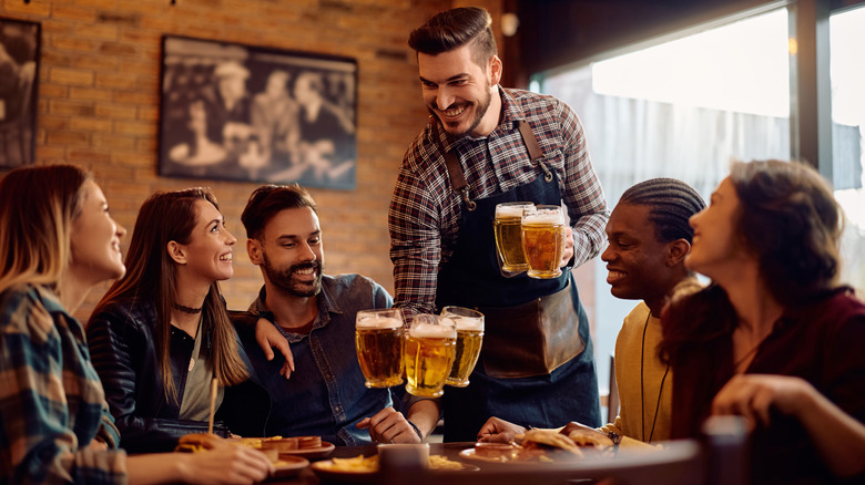 Bartender serving a handful of beers to large table
