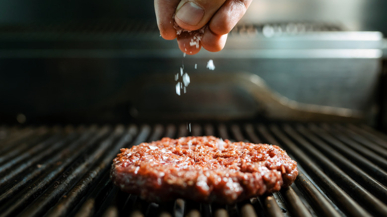 Chef salting burger patty 