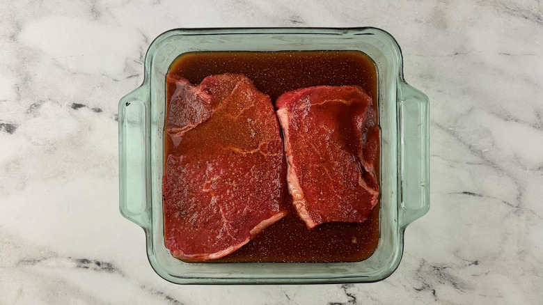 Steaks and marinade in glass dish
