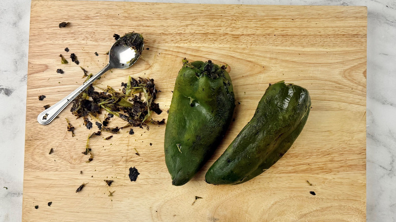 Spoon and peeled poblanos on wooden board