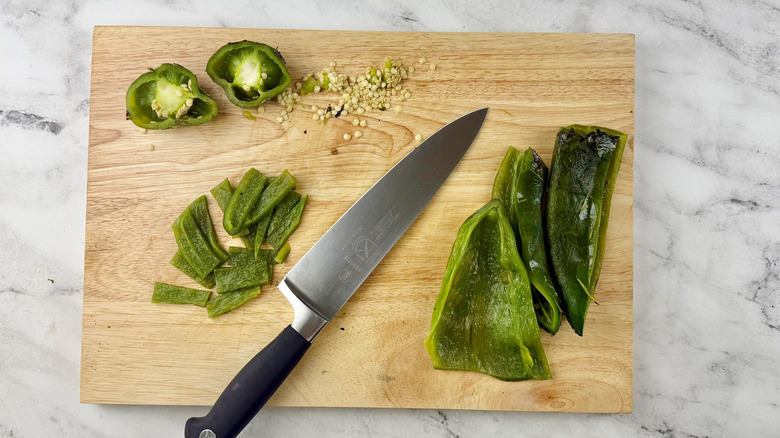 Knife and sliced poblanos on wooden board