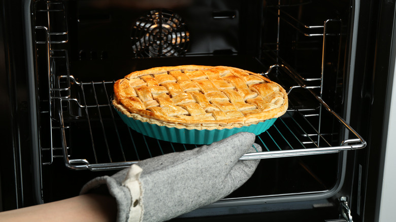 Woman removing homemade apple pie from the oven.