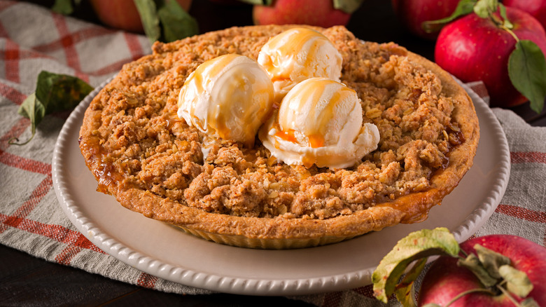 Apple crumble pie topped with three scoops of vanilla ice cream.