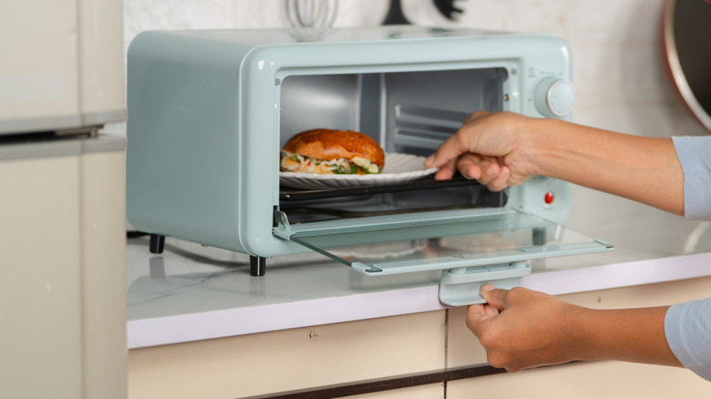 Person reheating sandwich in a toaster oven.