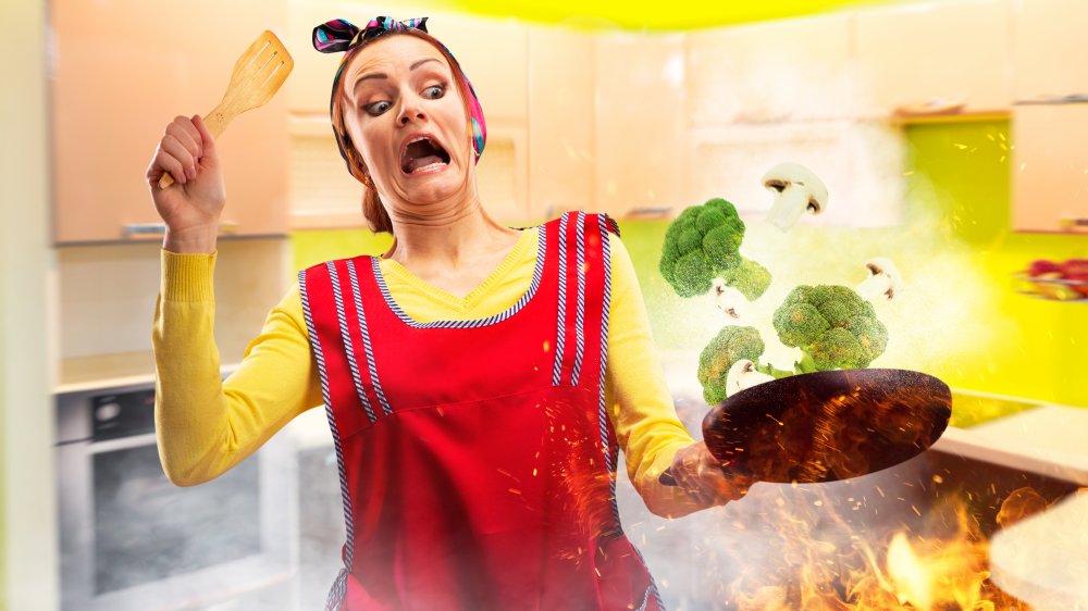 Woman catching pan of vegetables on fire