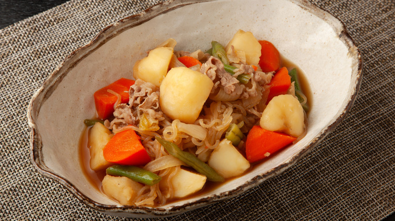 Beef and potato stew in a bowl on a placemat.