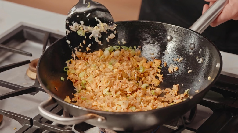 Someone stirs fried rice in a wok.