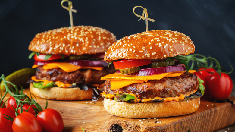 Two cheeseburgers on cutting board