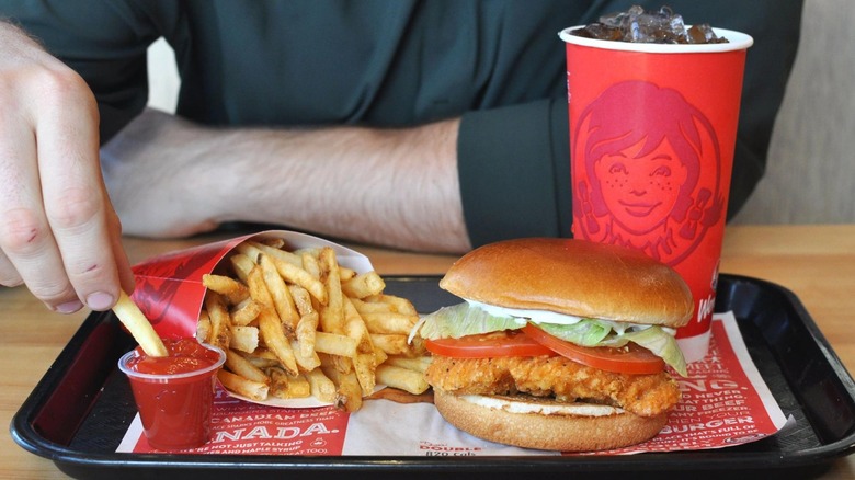Person eating a Wendy's Spicy Chicken Sandwich meal