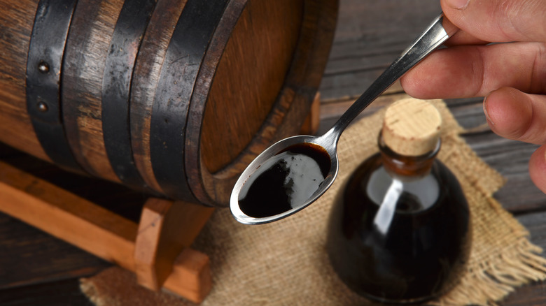 Balsamic vinegar next to the barrel and in a spoon