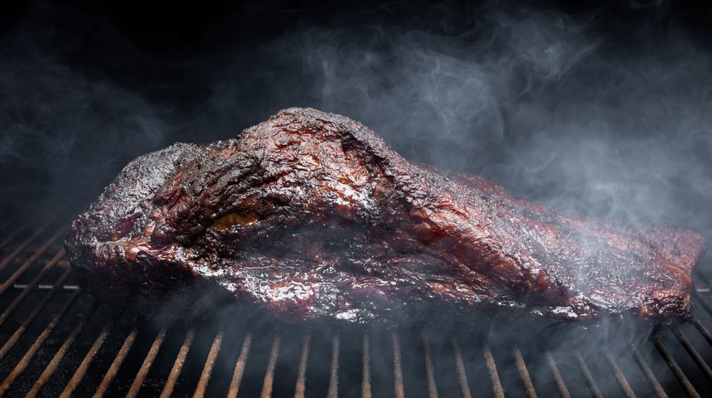 beef on a grill, billowing smoke