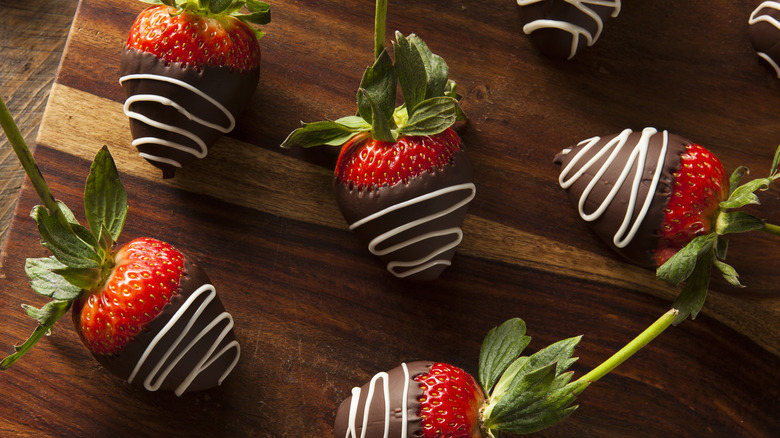 Chocolate-covered strawberries on wooden board