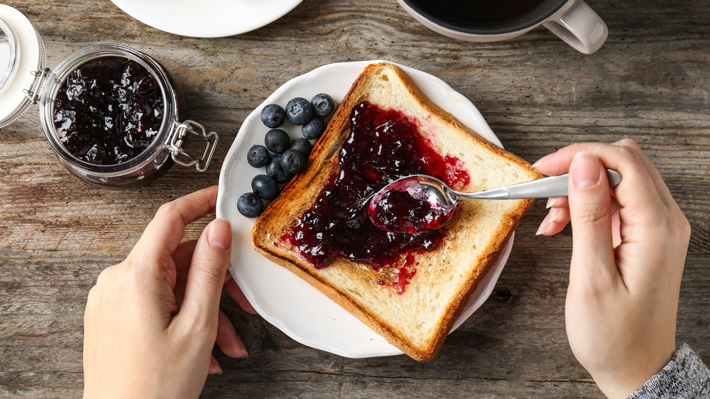 Woman spreading jam on toast