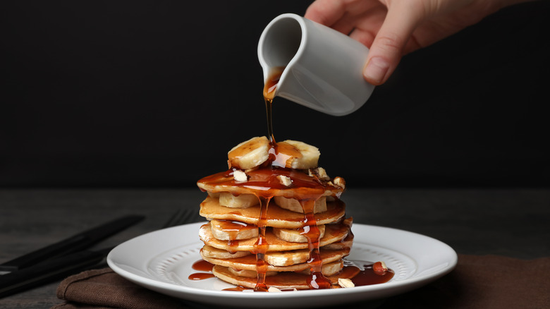 Pouring maple syrup on pancakes